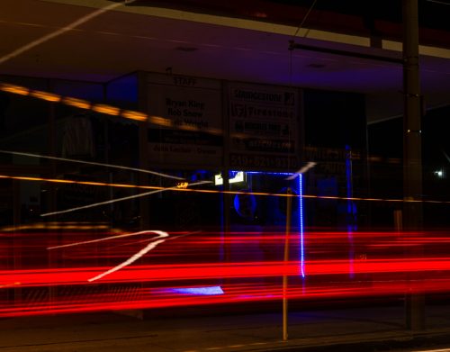 Cars pass by an automobile store on Water St at night